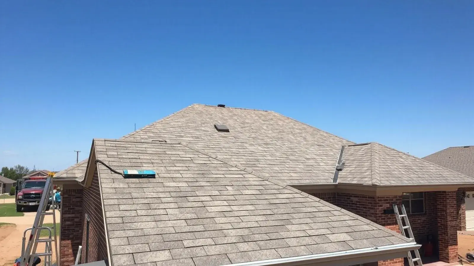 Sun-faded asphalt shingle roof on a brick ranch home in Lubbock, TX with a flat horizon and clear sky